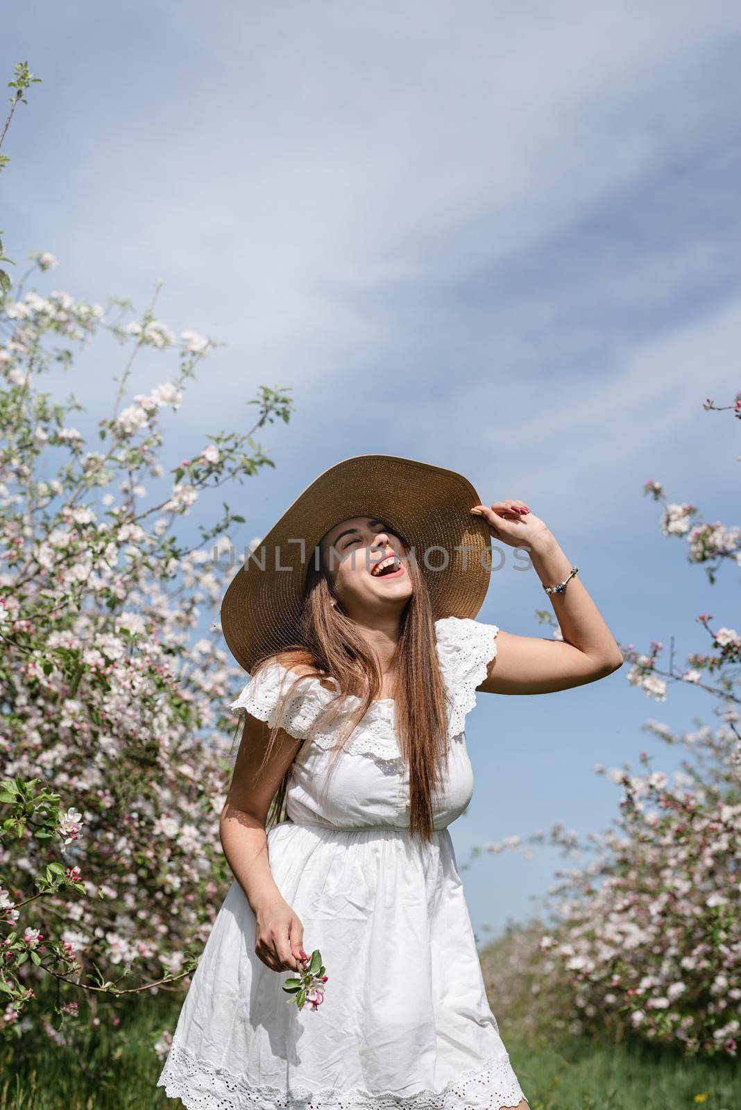 Young caucasian woman enjoying the flowering of an apple trees laughing by Desperada