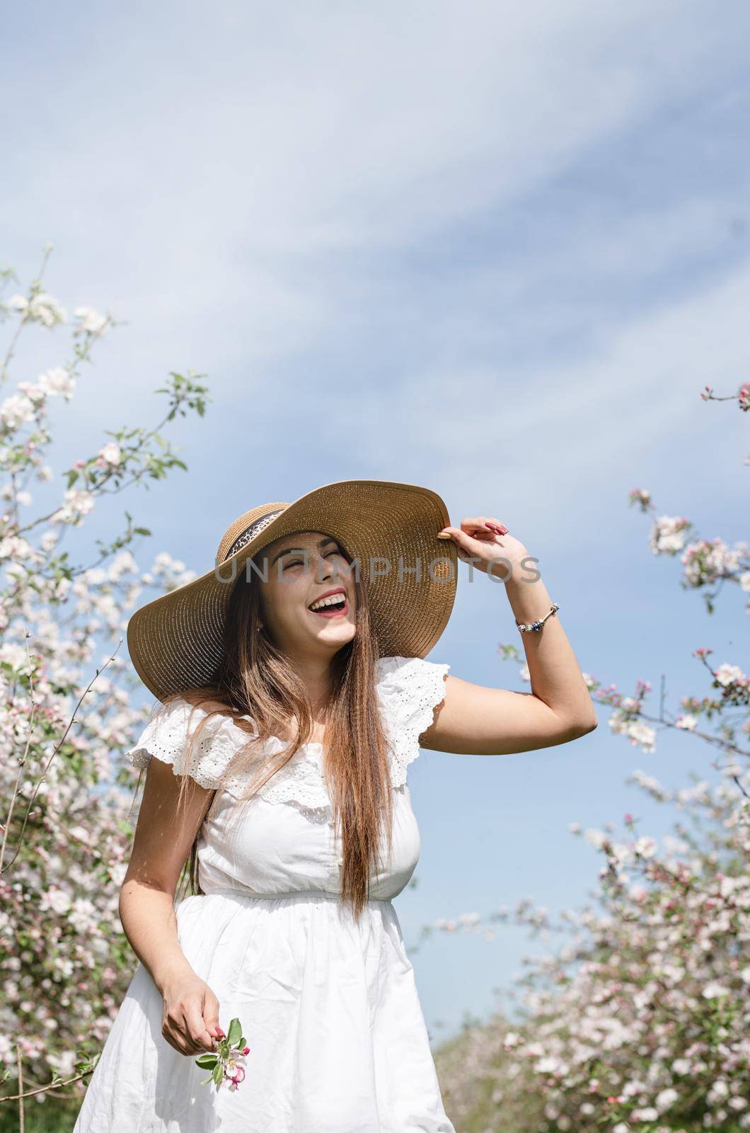 Spring concept. Nature.Young caucasian woman in white summer dress enjoying the flowering of an apple trees, walking in spring apple gardens