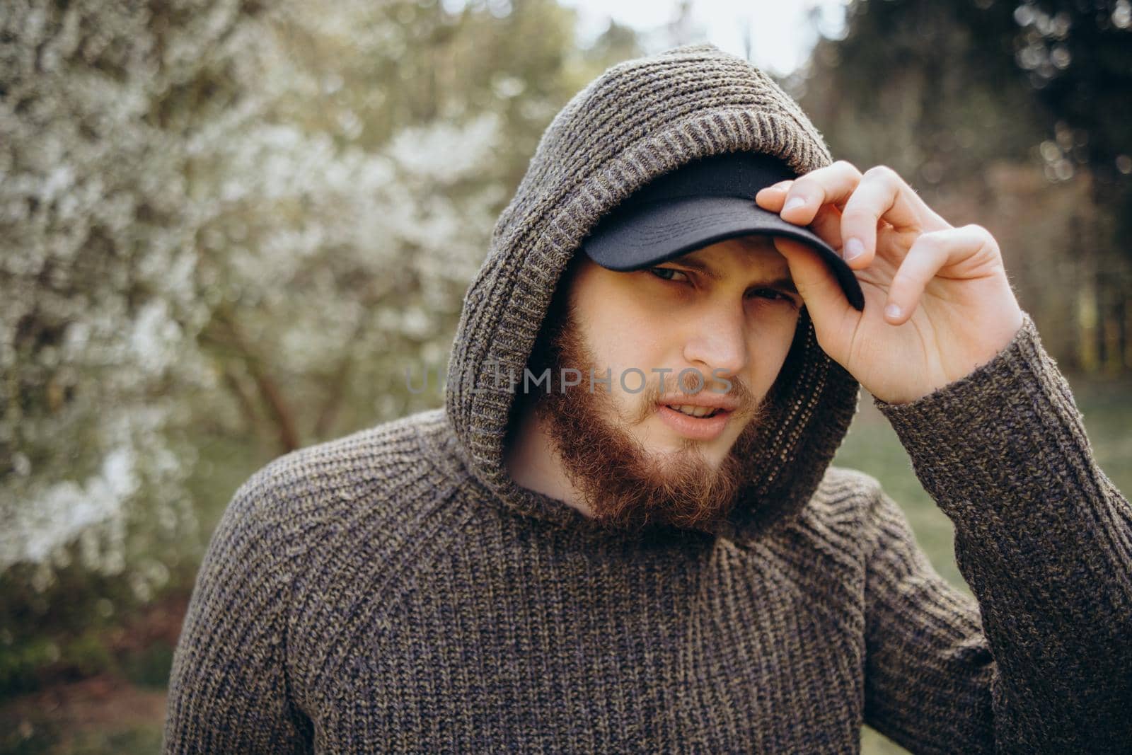 Headshot of a man wearing a brown hooded top with an intense stare at the park.