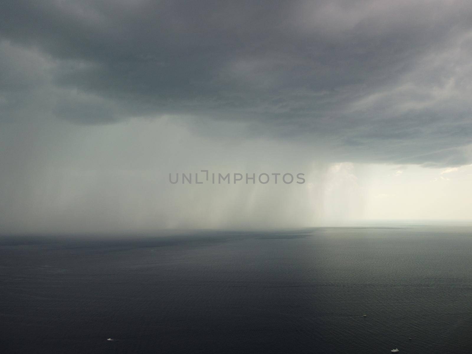 Aerial view footage of rain clouds over sea ocean Black clouds in bad weather day over sea surface High angle view nature view Apocalypse. Storm Large freight dark gloomy rain clouds over a calm sea.