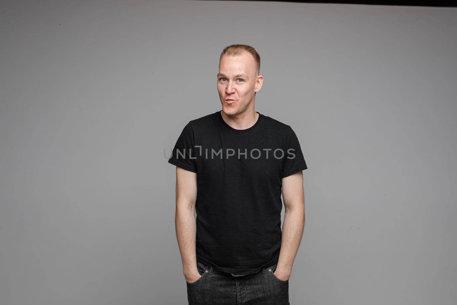 picture of handsome caucasian male keeping hands in the pockets isolated over the grey background