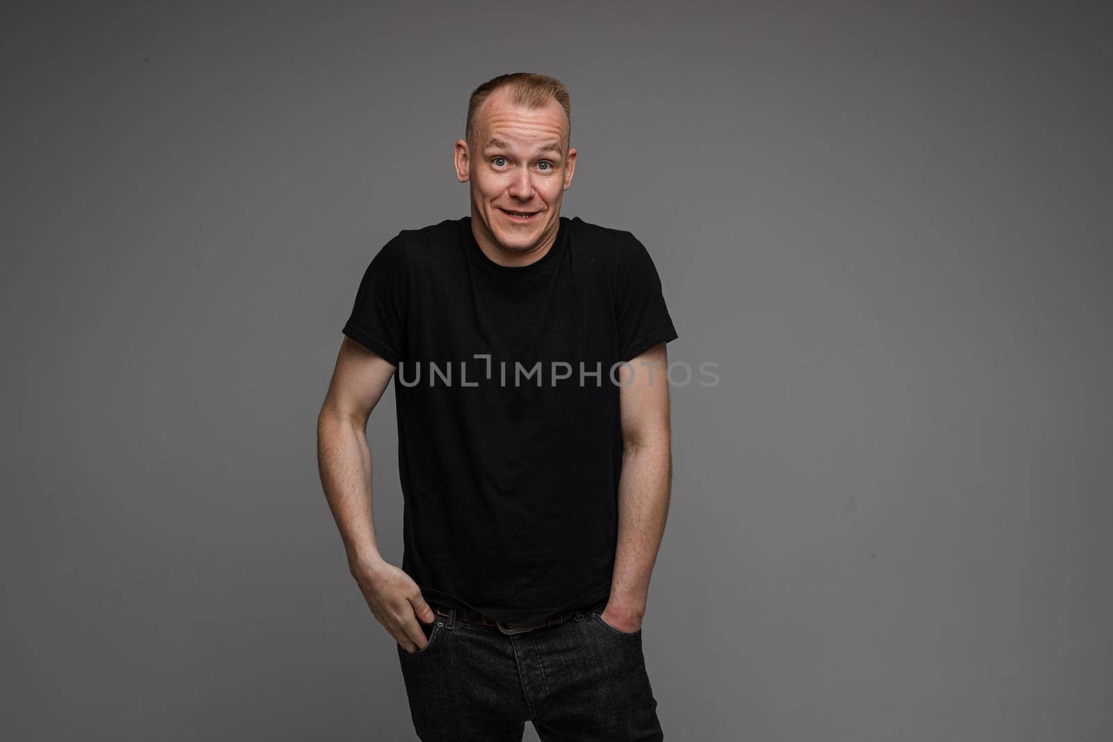 picture of handsome caucasian male keeping hands in the pockets isolated over the grey background