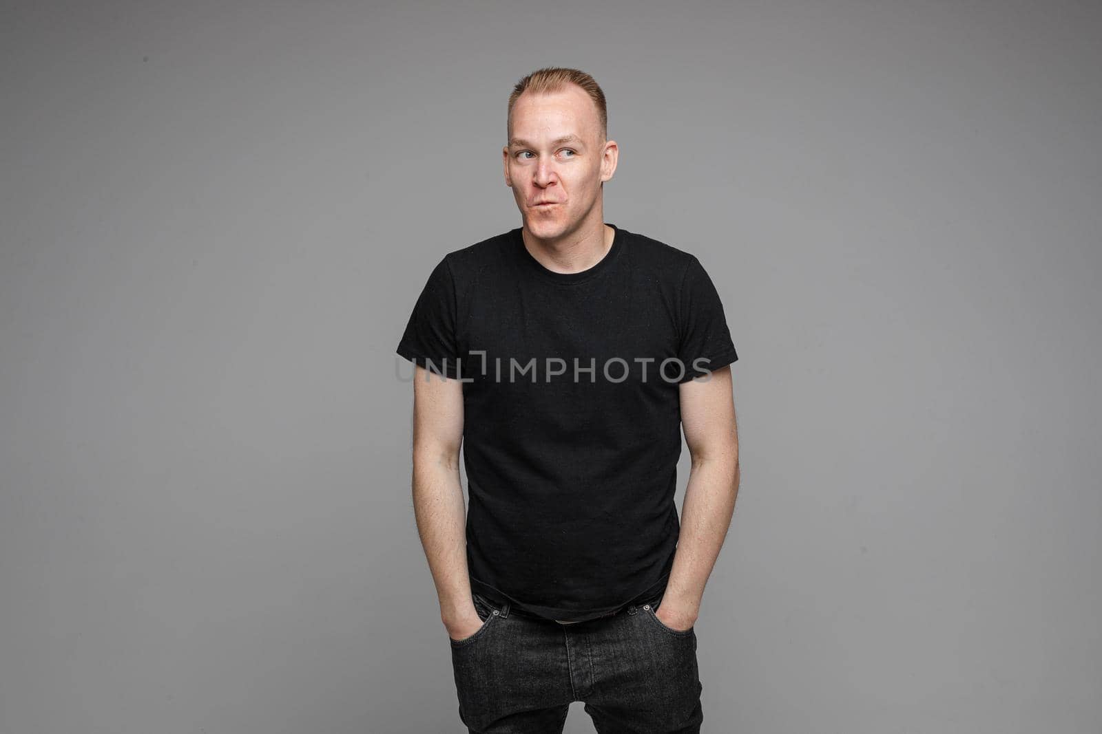 picture of handsome caucasian male keeping hands in the pockets isolated over the grey background