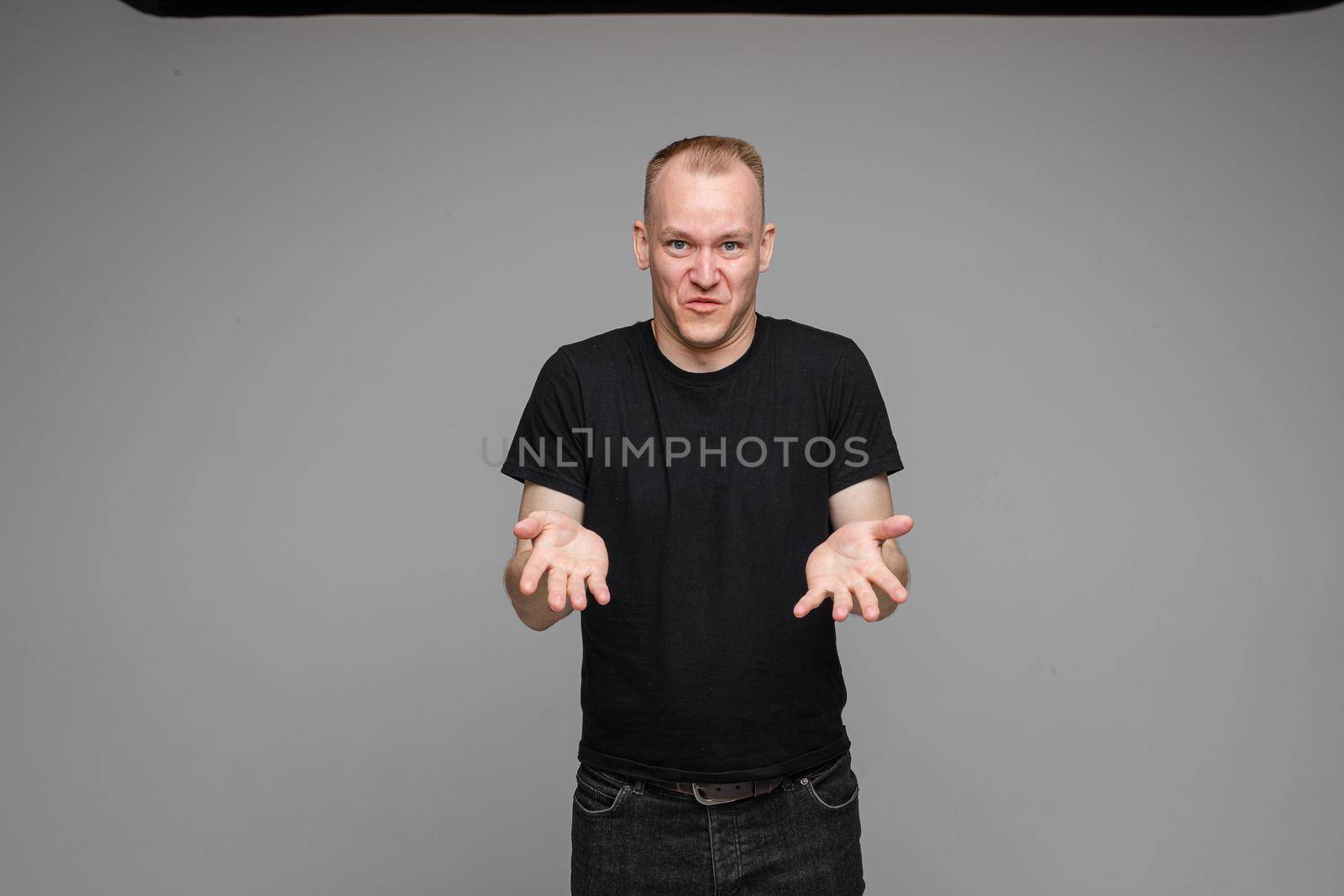 picture of handsome caucasian male explain something keeping hands in front of him isolated on grey background