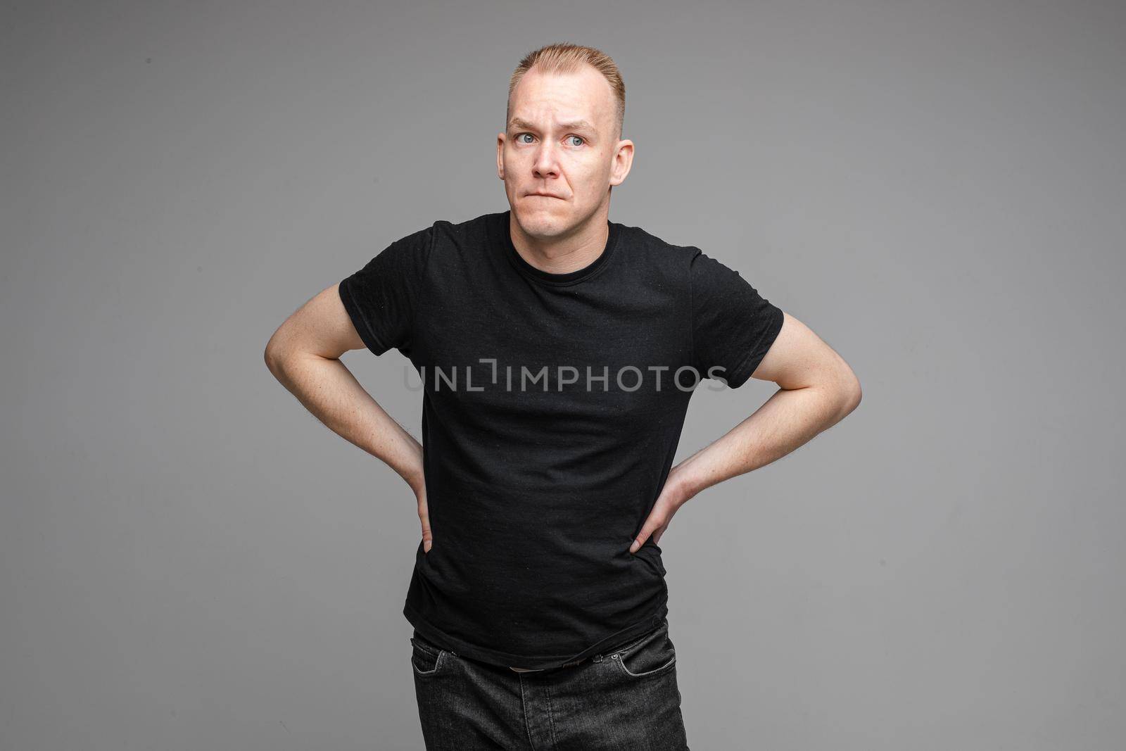 Waist-up photo of adult man in black shirt making a beaconing gesture with his hand and looking at the camera