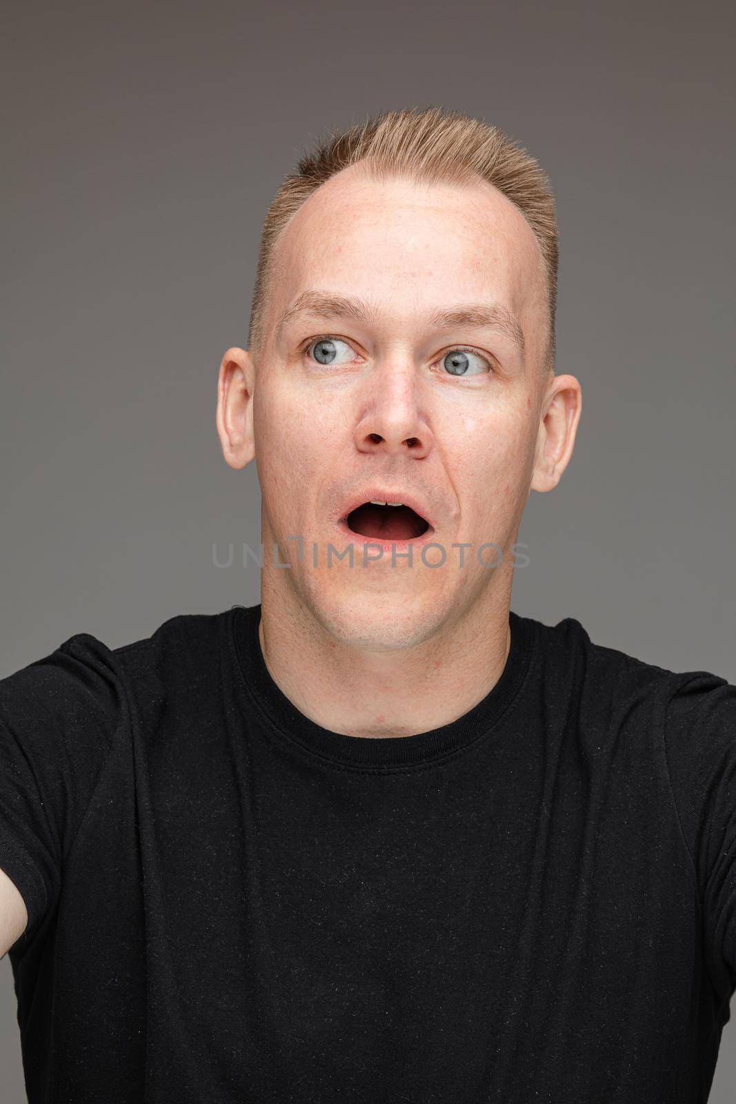 Close-up photo of a fair-haired man opening his mouth in surprise
