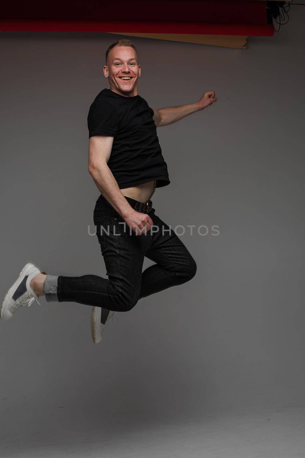 funny man jumps and rejoices in studio on white background, backstage of a photosession by StudioLucky