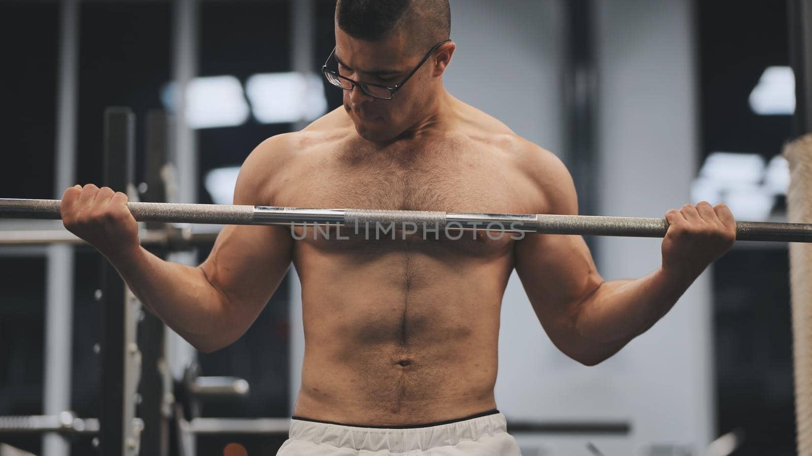 Young Arab man pumping biceps in the gym. by DovidPro