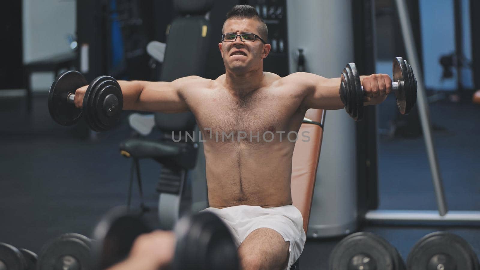Arab male athlete improves his shoulders with dumbbell breeding