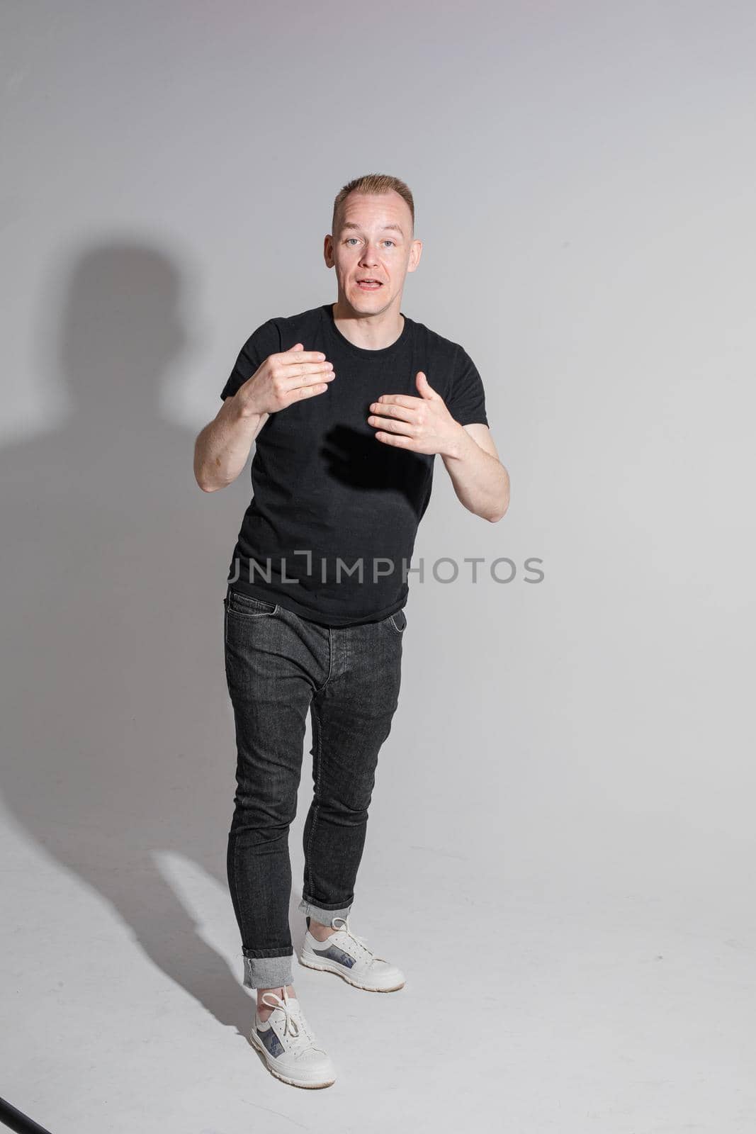 Staged photo of Caucasian man standing near grey backdrop by StudioLucky