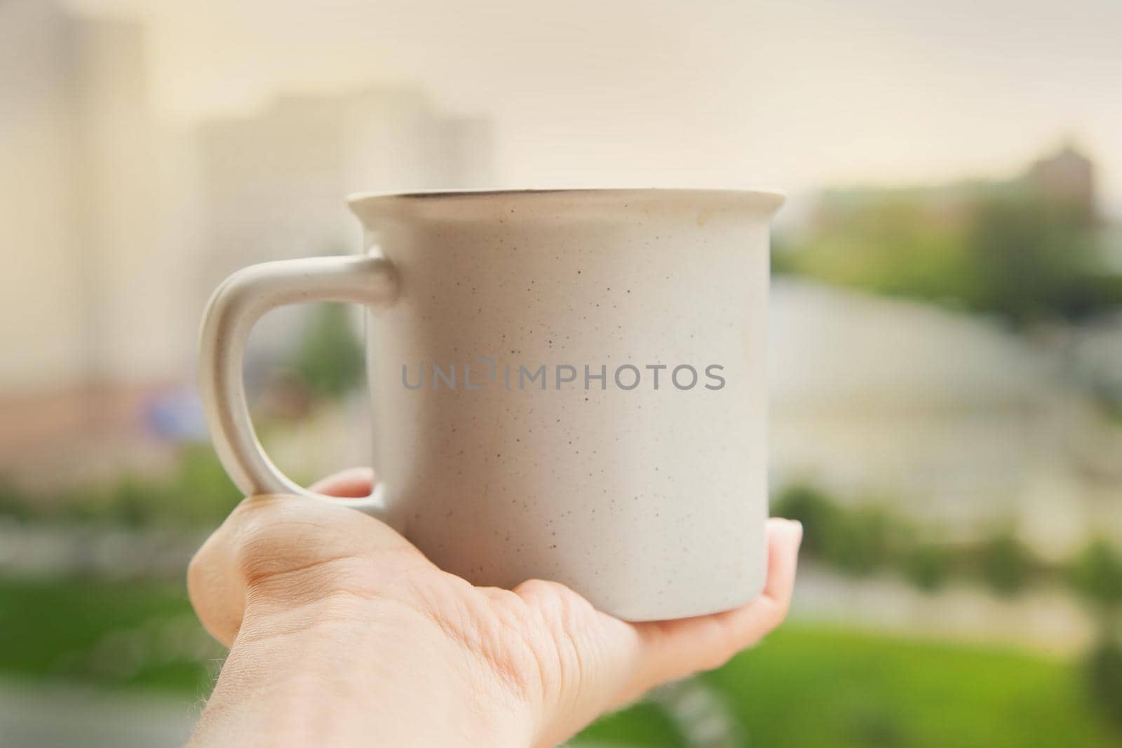 Hand holding cup with urban landscape on backckground