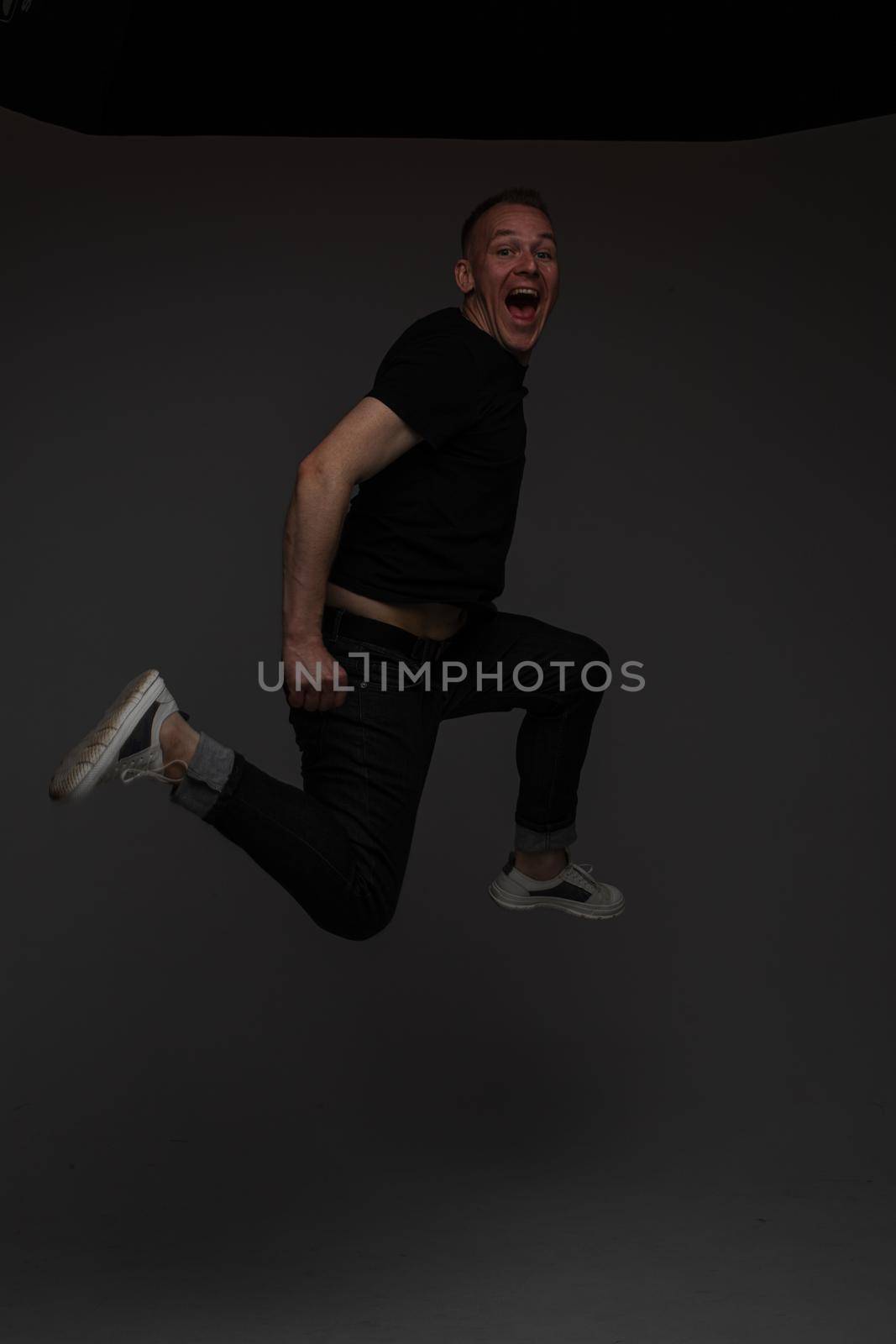 funny man jumps and rejoices in studio on white background, backstage of a photosession by StudioLucky