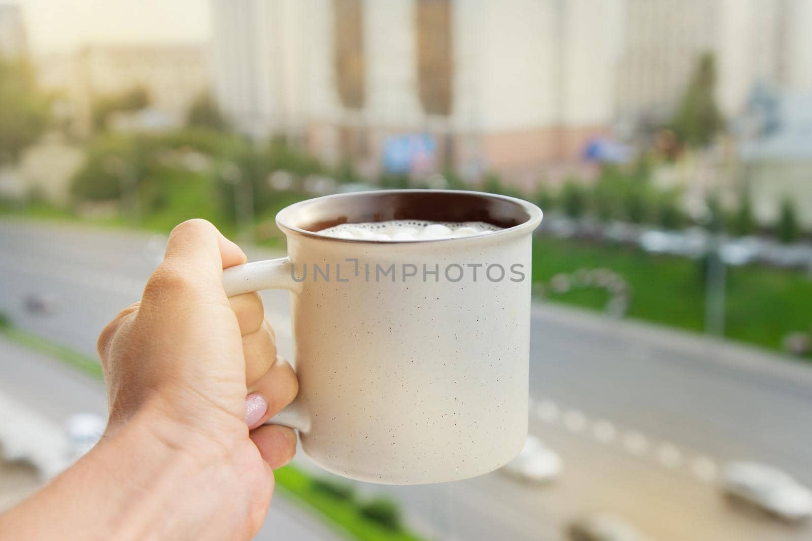 Hand holding cup with urban landscape on backckground