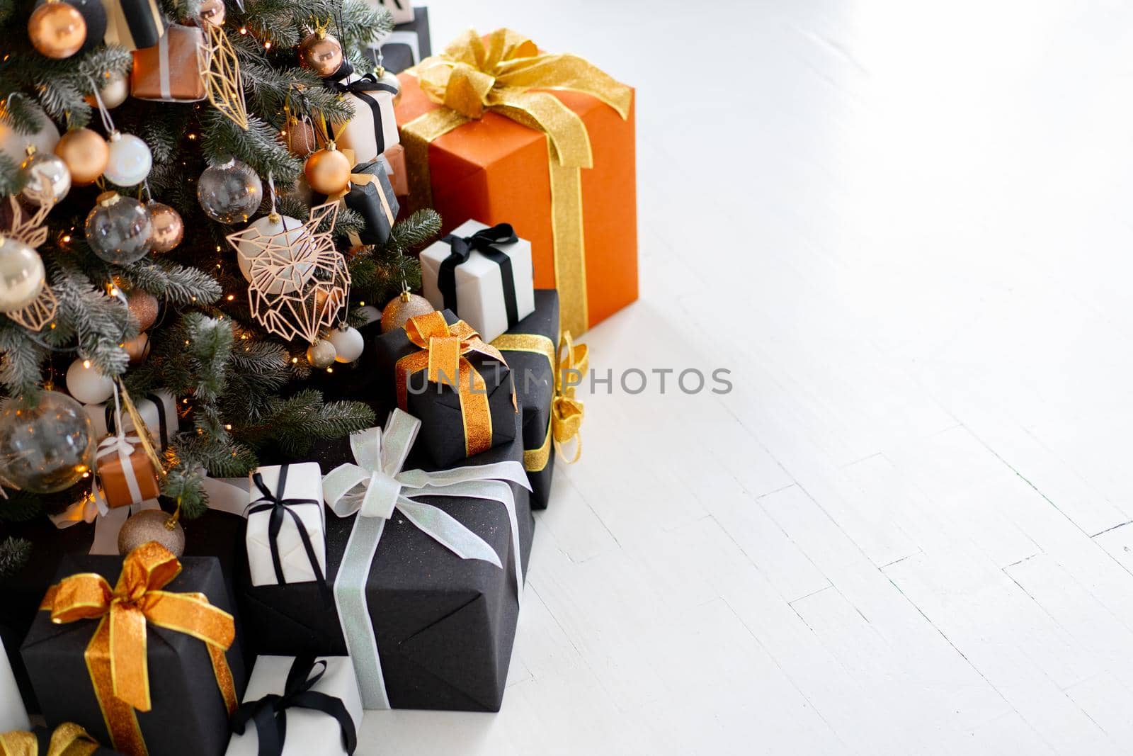 Christmas present gift box stacked close up. Holiday sale concept. Many gift box black, white, orange color with gold ribbon and light garland