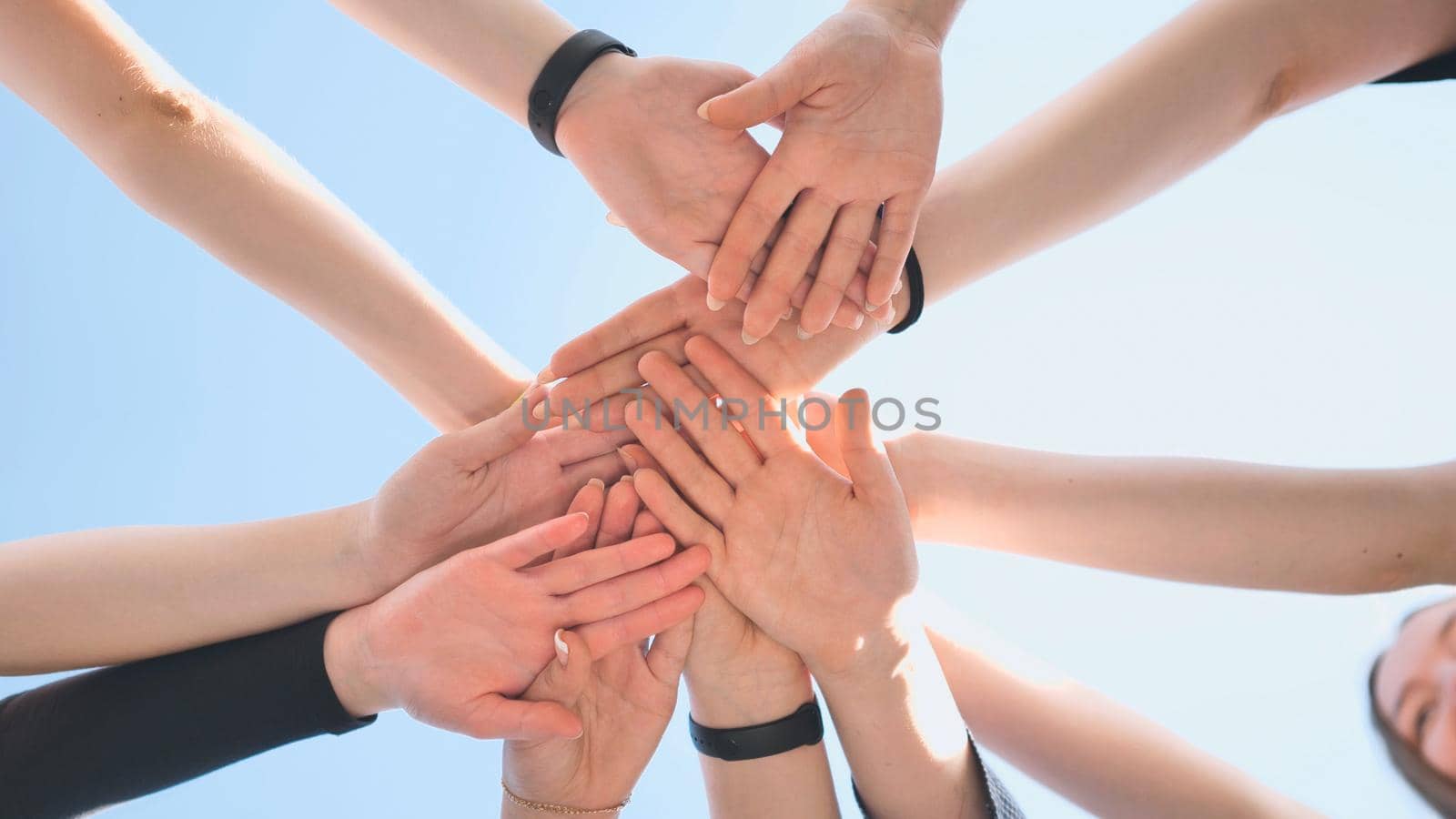 Cheerful girls join hands together as a sign of unity and joint successful work. Teamwork stacking hand concept