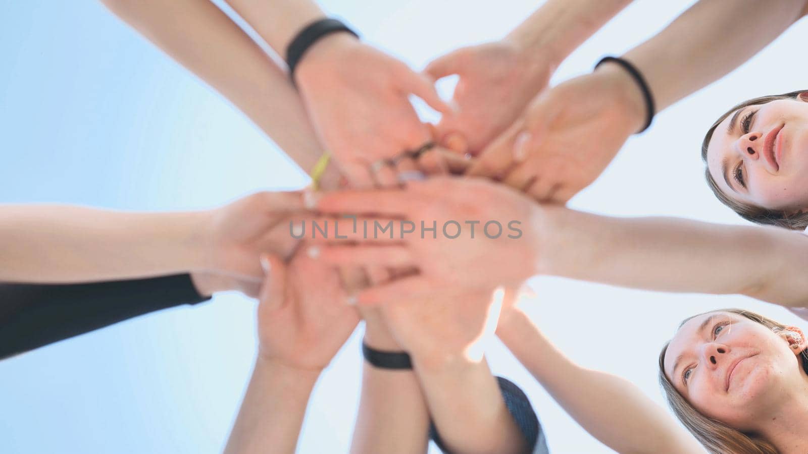 Cheerful girls join hands together as a sign of unity and joint successful work. Teamwork stacking hand concept