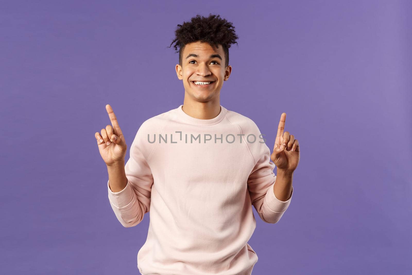 Waist-up portrait of dreamy, handsome 25s young hispanic man seeing good promotion, best deal or offer from online shop, pointing fingers top advertisement, looking up with satisfied smile.