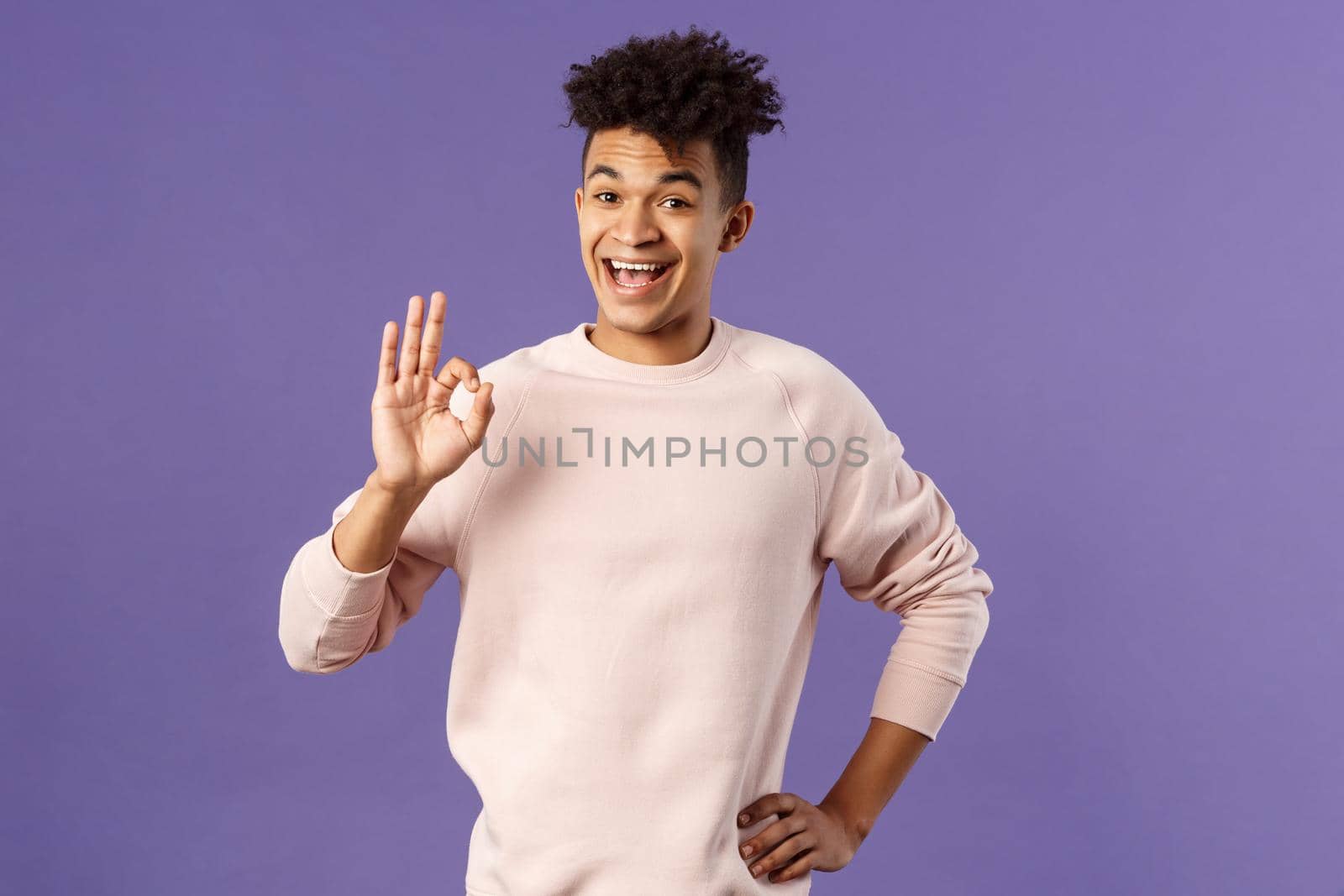 Relax its okay. Portrait of carefree, unbothered young man have everything under control, assure and guarantee job will be done, recommend product, being pleased, purple background by Benzoix