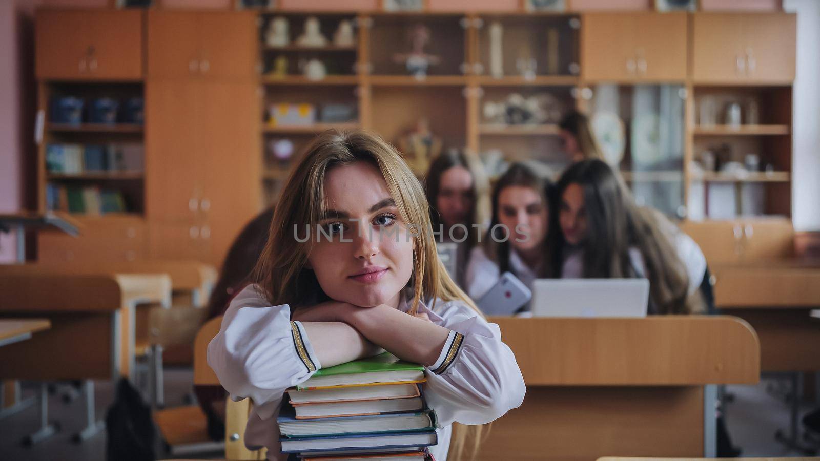 A student poses with textbooks at her desk in her class