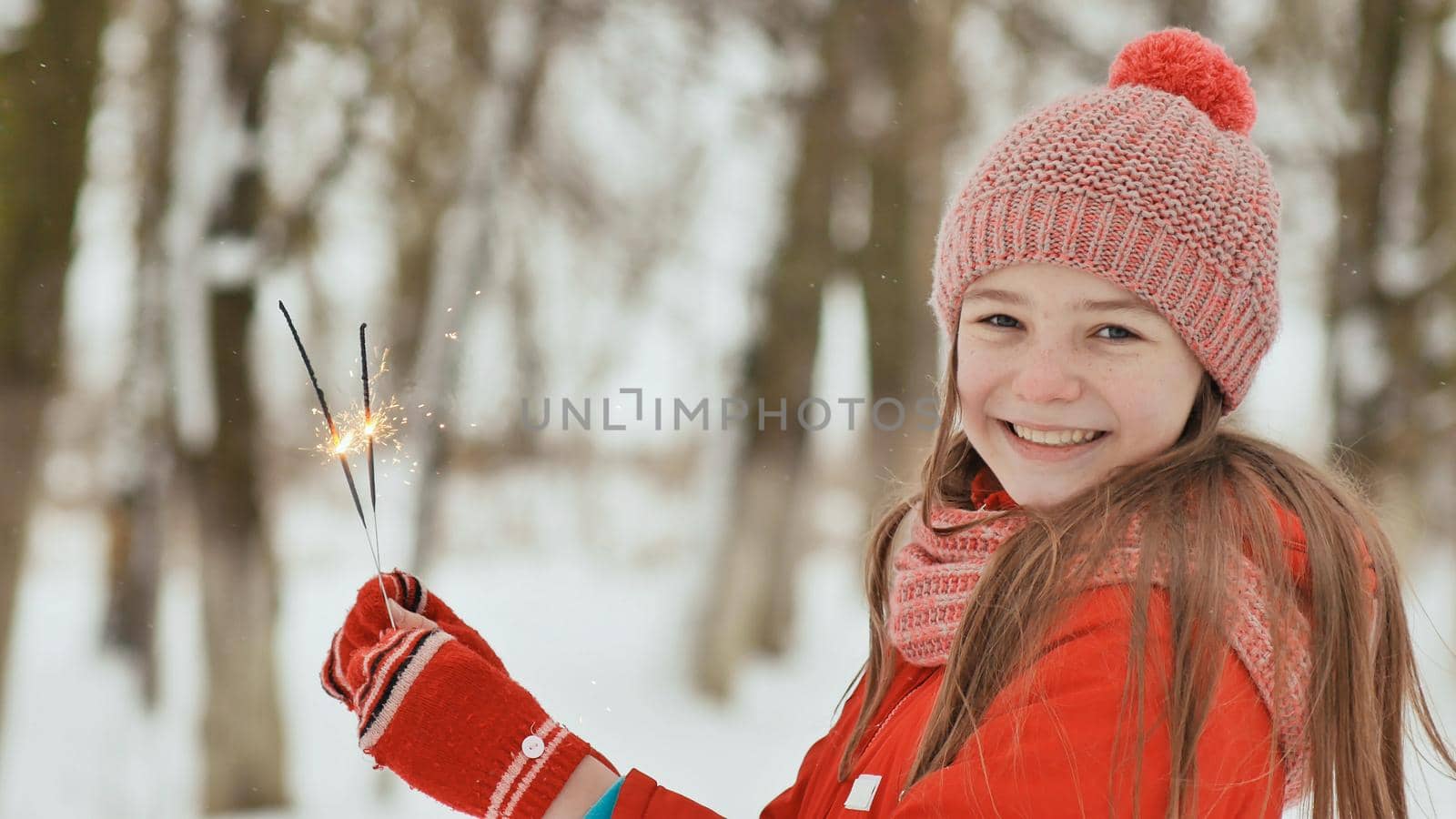 The charming young schoolgirl joyfully holds in her hands a packaged box with a gift in the winter forest. In anticipation of the New Year holidays