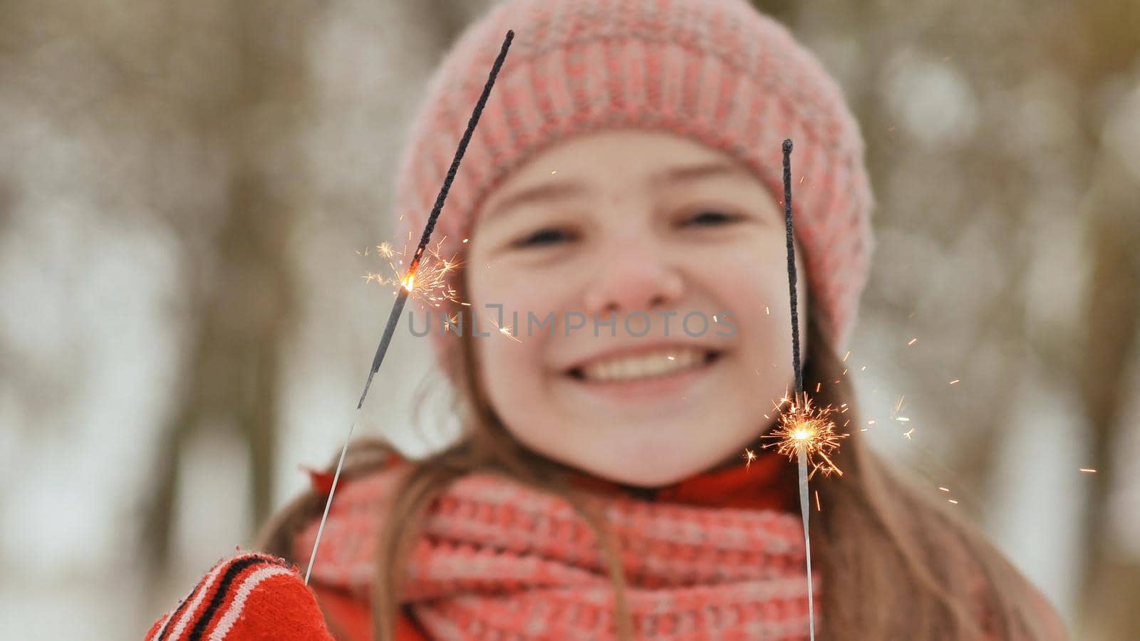 A happy young schoolgirl with sparkling sparks of bengal lights among the winter forest. On the eve of New Year's holidays