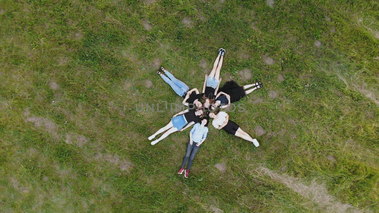 Girls friends lie on the grass like a flower