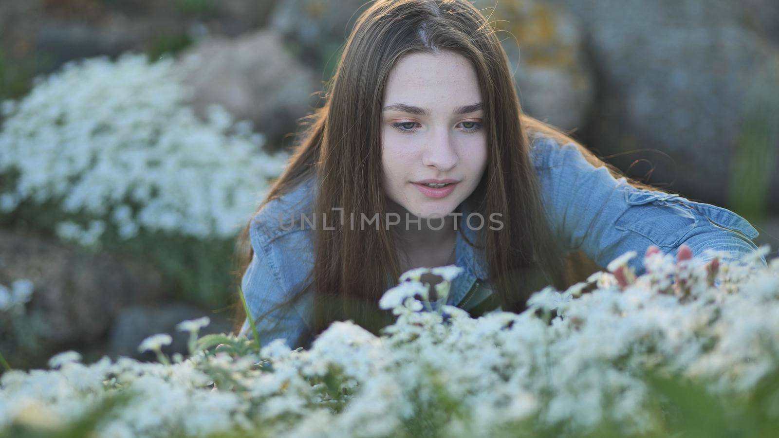 Long-haired girl sniffs white flowers and smiles