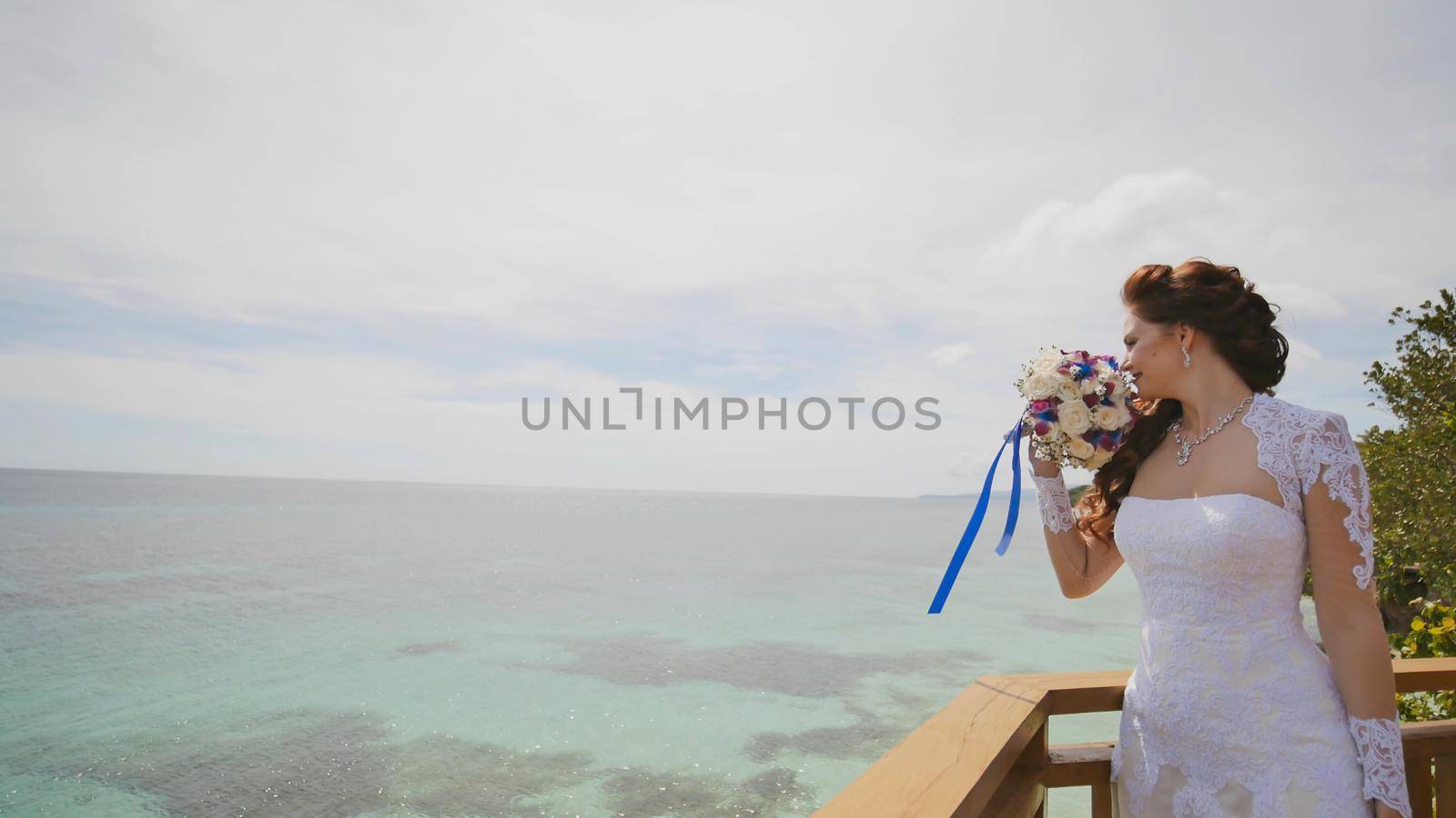 A dazzling bride enjoys happiness from the height of the balcony overlooking the ocean and reefs. Flight of love. Exotic Filipino Tropics. Shooting in motion. by DovidPro