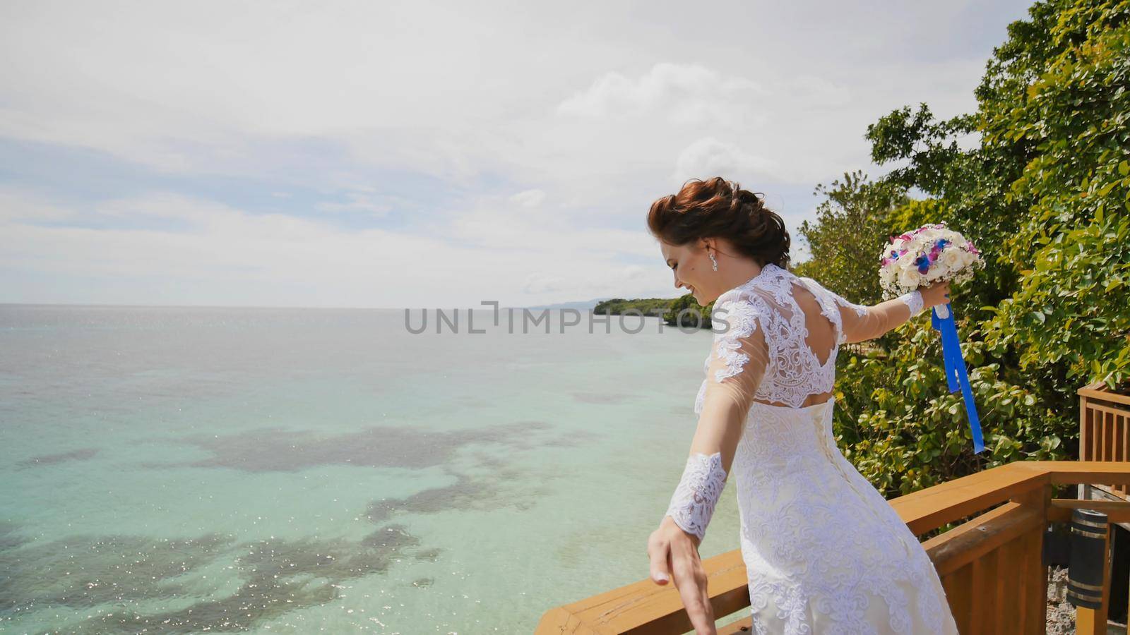 A dazzling bride enjoys happiness from the height of the balcony overlooking the ocean and reefs. Flight of love. Exotic Filipino Tropics. Shooting in motion. by DovidPro