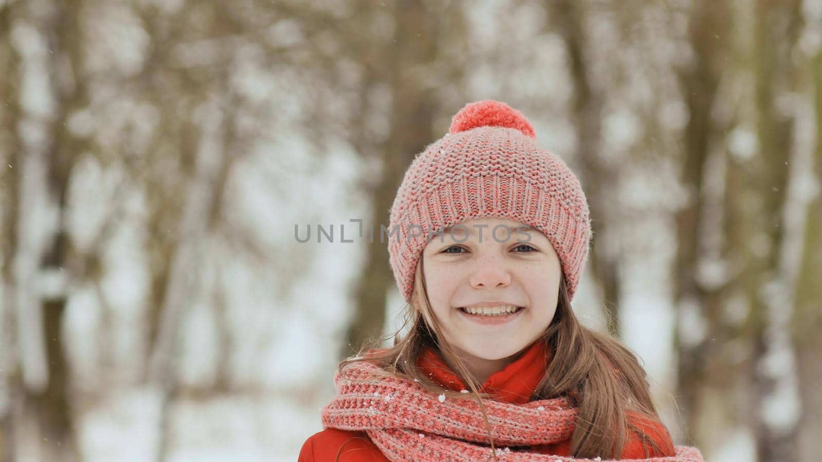 A young schoolgirl joyfully throws a snowball and breaks it with a palm when it falls. Emotions of joy. Winter fun in nature in the forest. by DovidPro