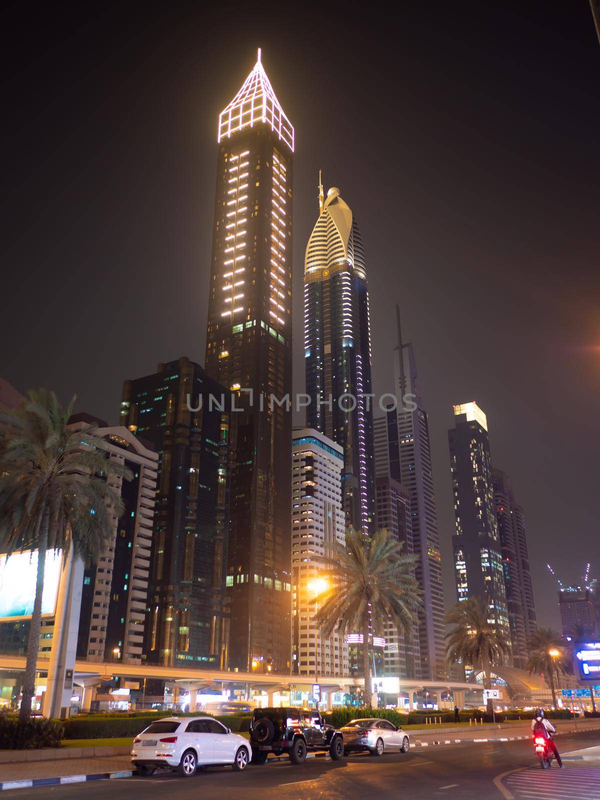 Dubai skyscrapers at night with road traffic late at night. by DovidPro