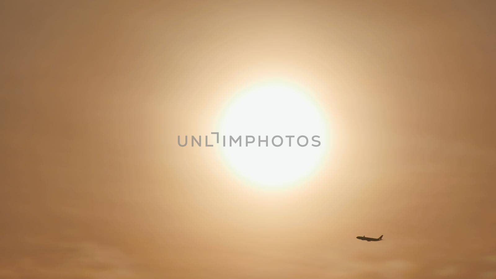 Take off the plane in the distance against the background of sunrise or sunset. Silhouette of an airplane. Airplane in the sky at sunset. by DovidPro