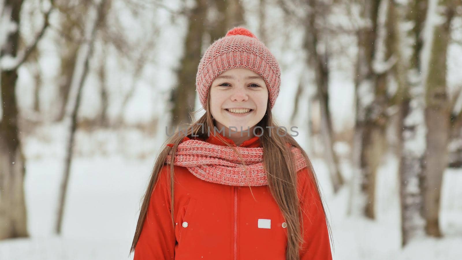 A teenage girl with freckles on her face happily smiles into the camera. A background of a winter forest landscape. by DovidPro