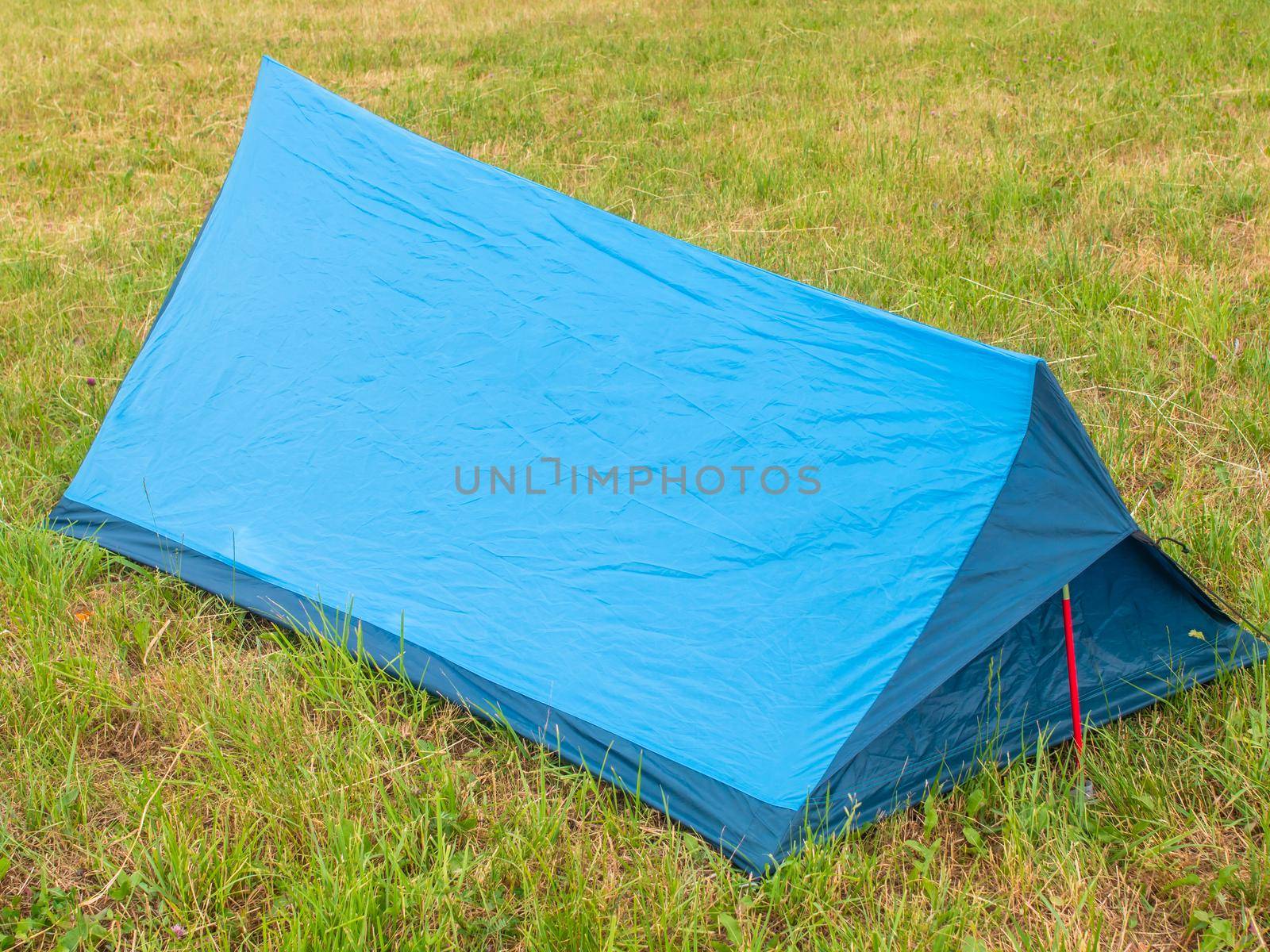 Tourist tent of blue color on green grass