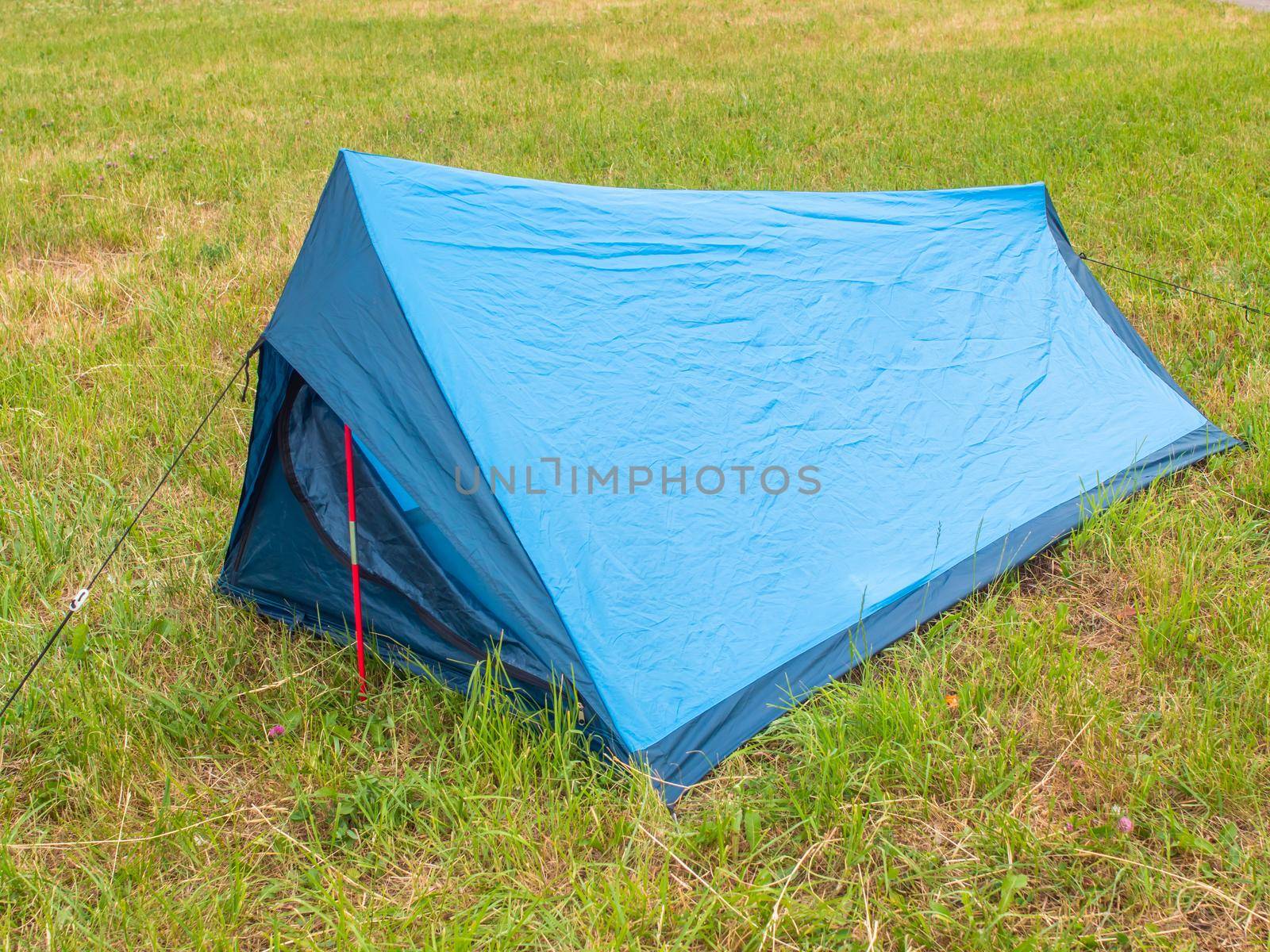 Tourist tent of blue color on green grass