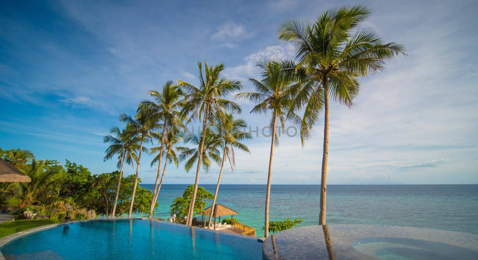 Outdoor swimming pool in a tropical country Philippines with palm trees. Evening time.