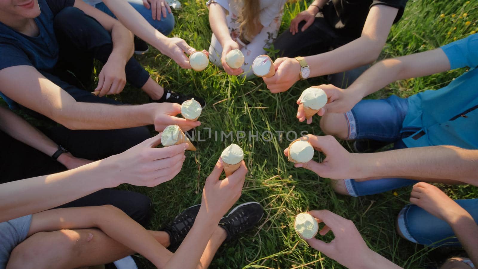 Nine friends clink glasses of ice cream. Hands close-up. by DovidPro