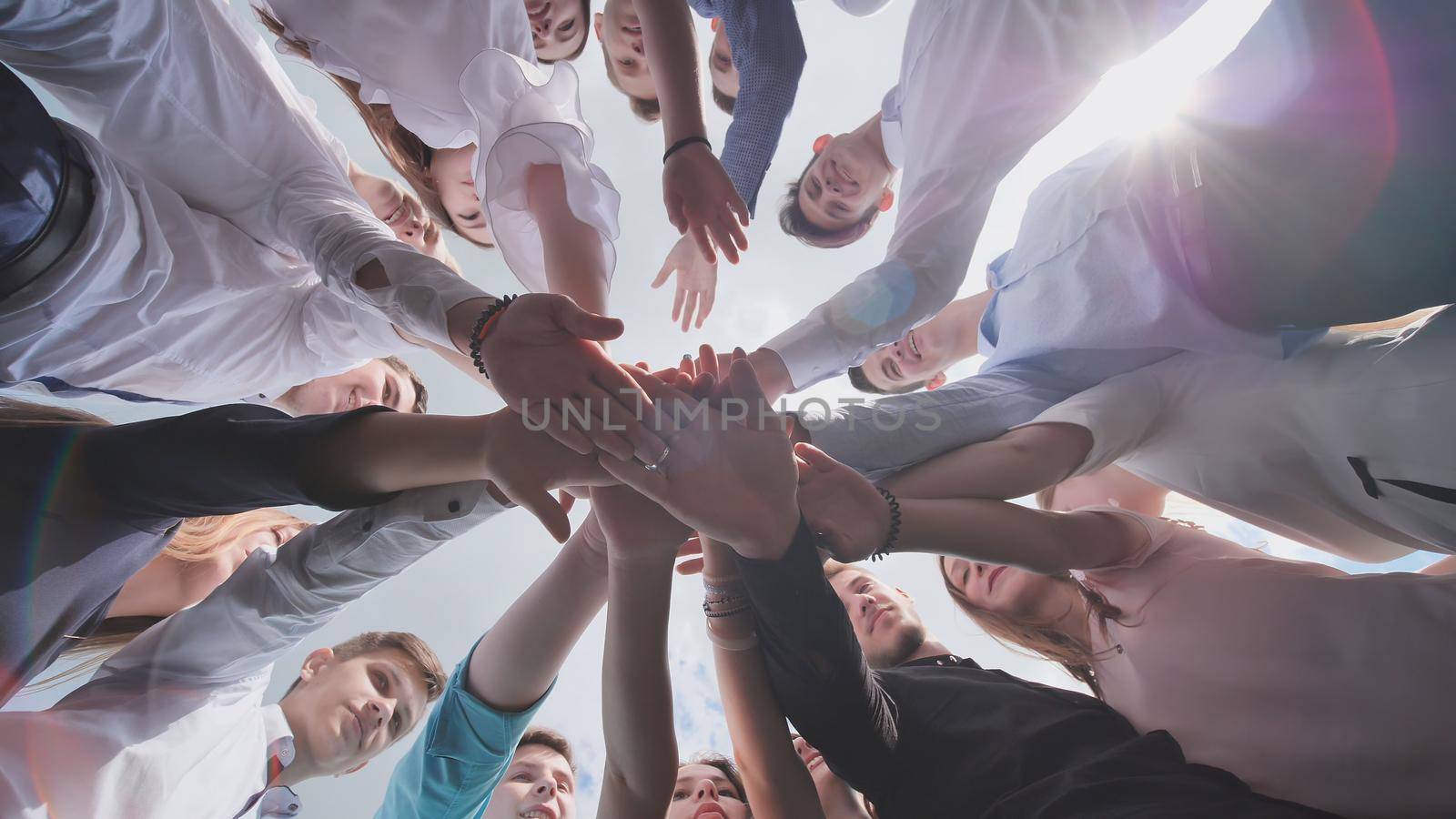 Students graduates gather around and lay their hands in a sign of successful work