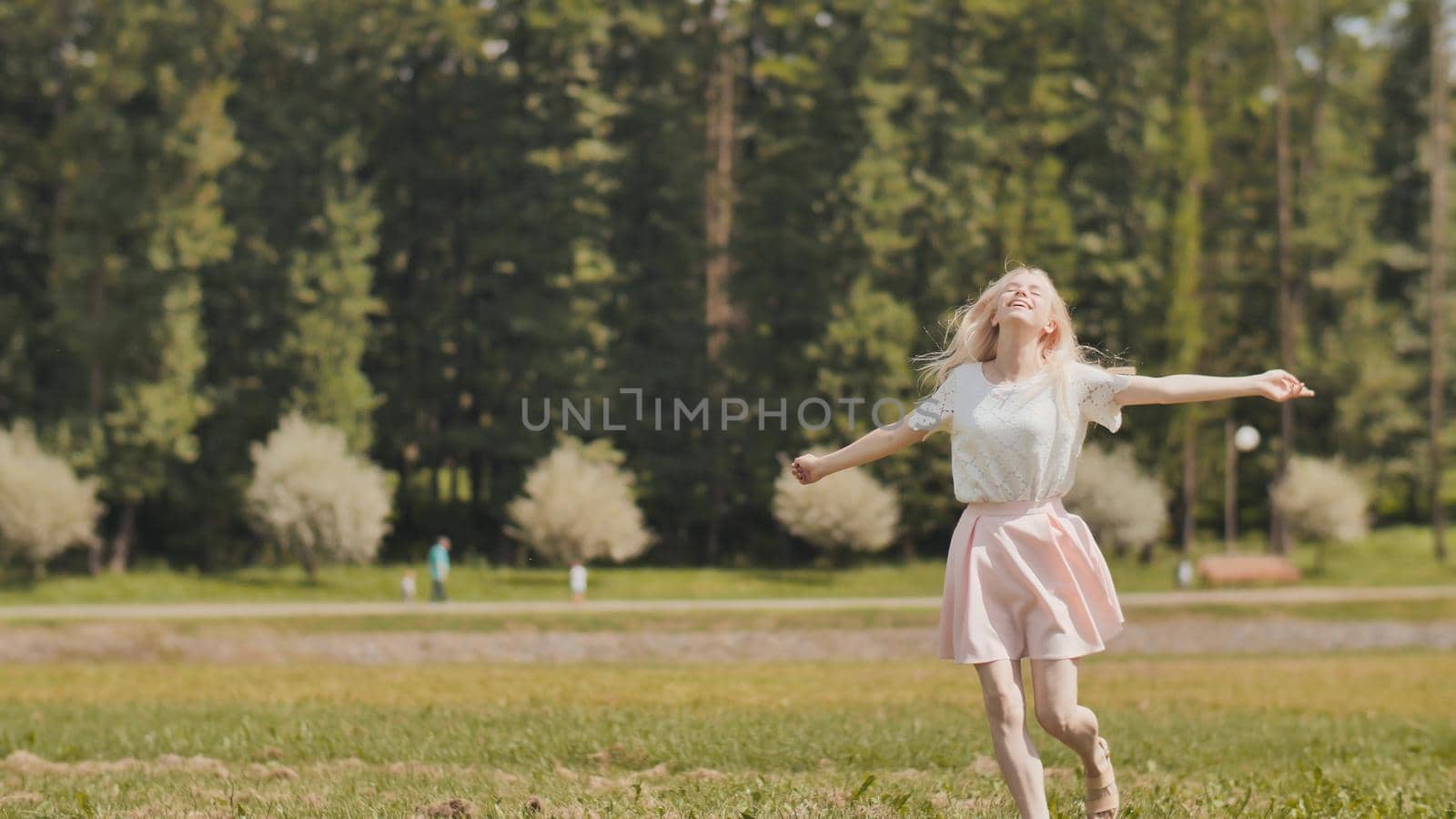 A happy young russian girl is running in the city park. by DovidPro