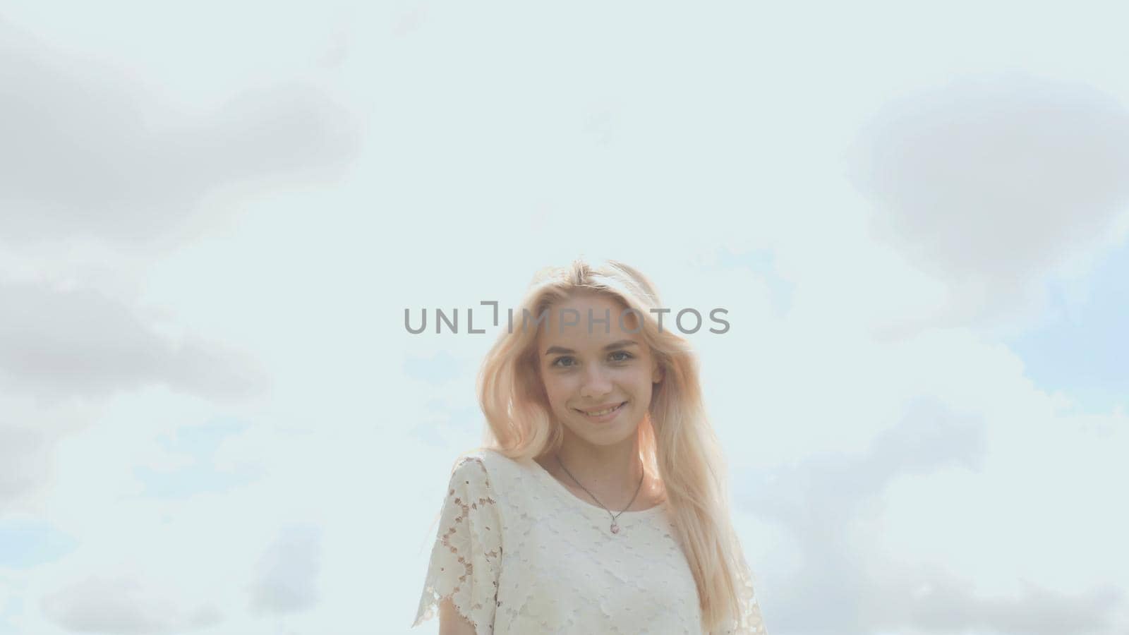 Young Russian girl blonde posing against a white sky on a summer day