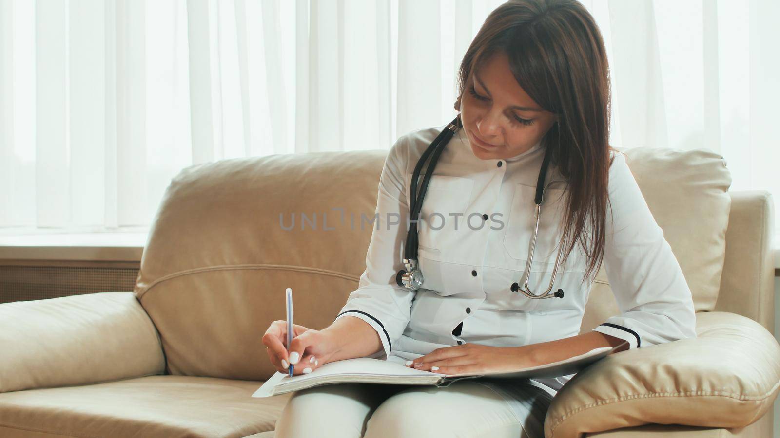 A young woman doctor writes prescription medications and treatment advice. by DovidPro