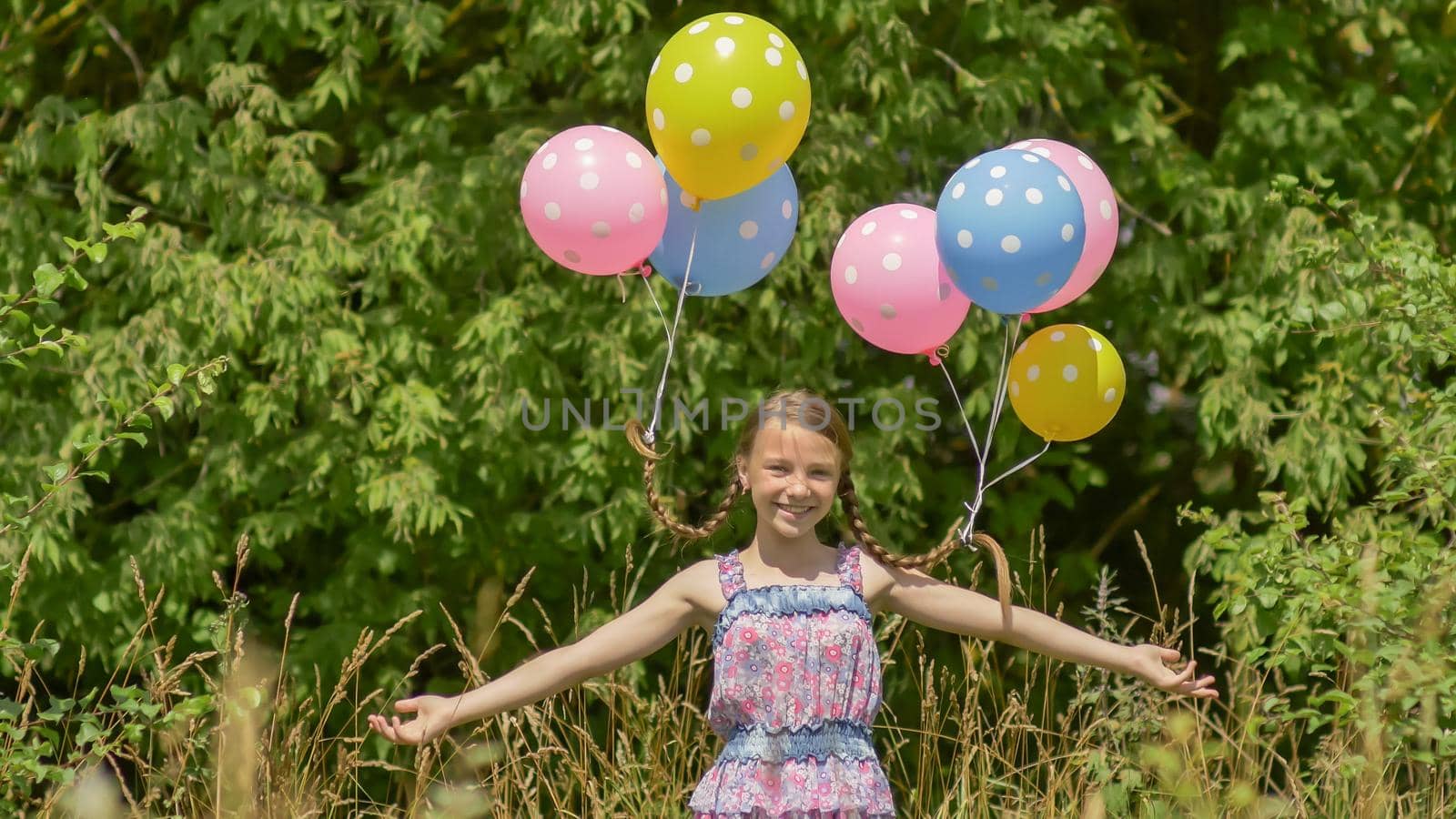 Cheerful and pretty girl with colorful balls attached to her hair and braids on her head. Funny idea with balloons