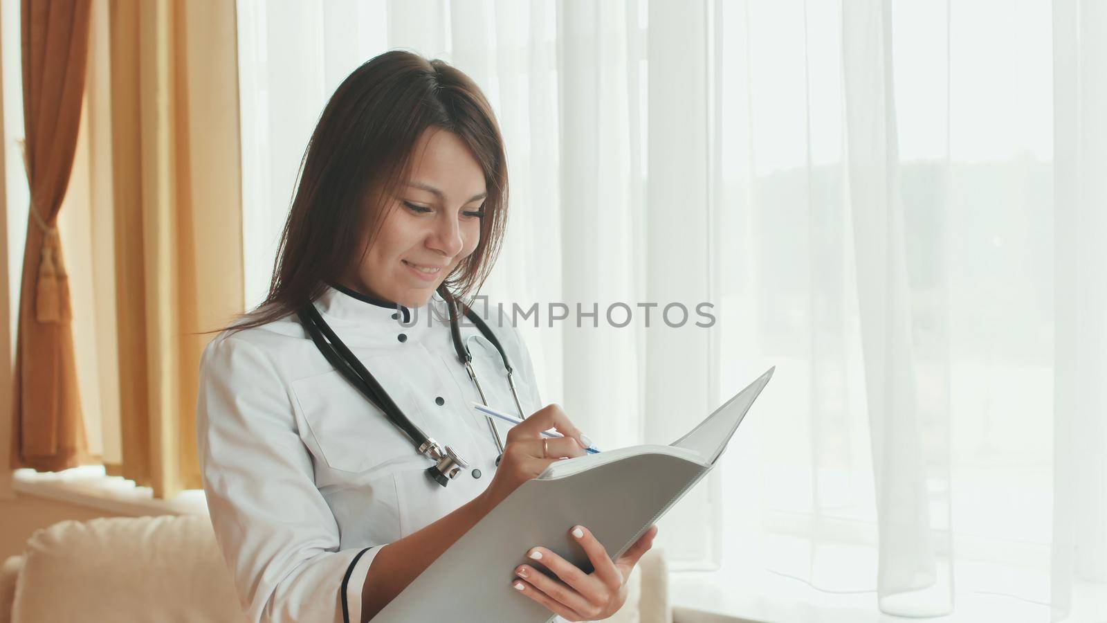 A young woman doctor writes in a summary in a good mood