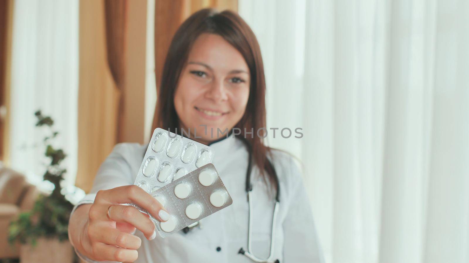 A young girl doctor demonstrates in the hands of a package of pills. by DovidPro