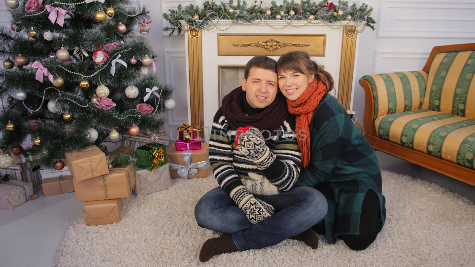 A young young couple gives presents to the camera for the viewer. Christmas and New Year theme. by DovidPro
