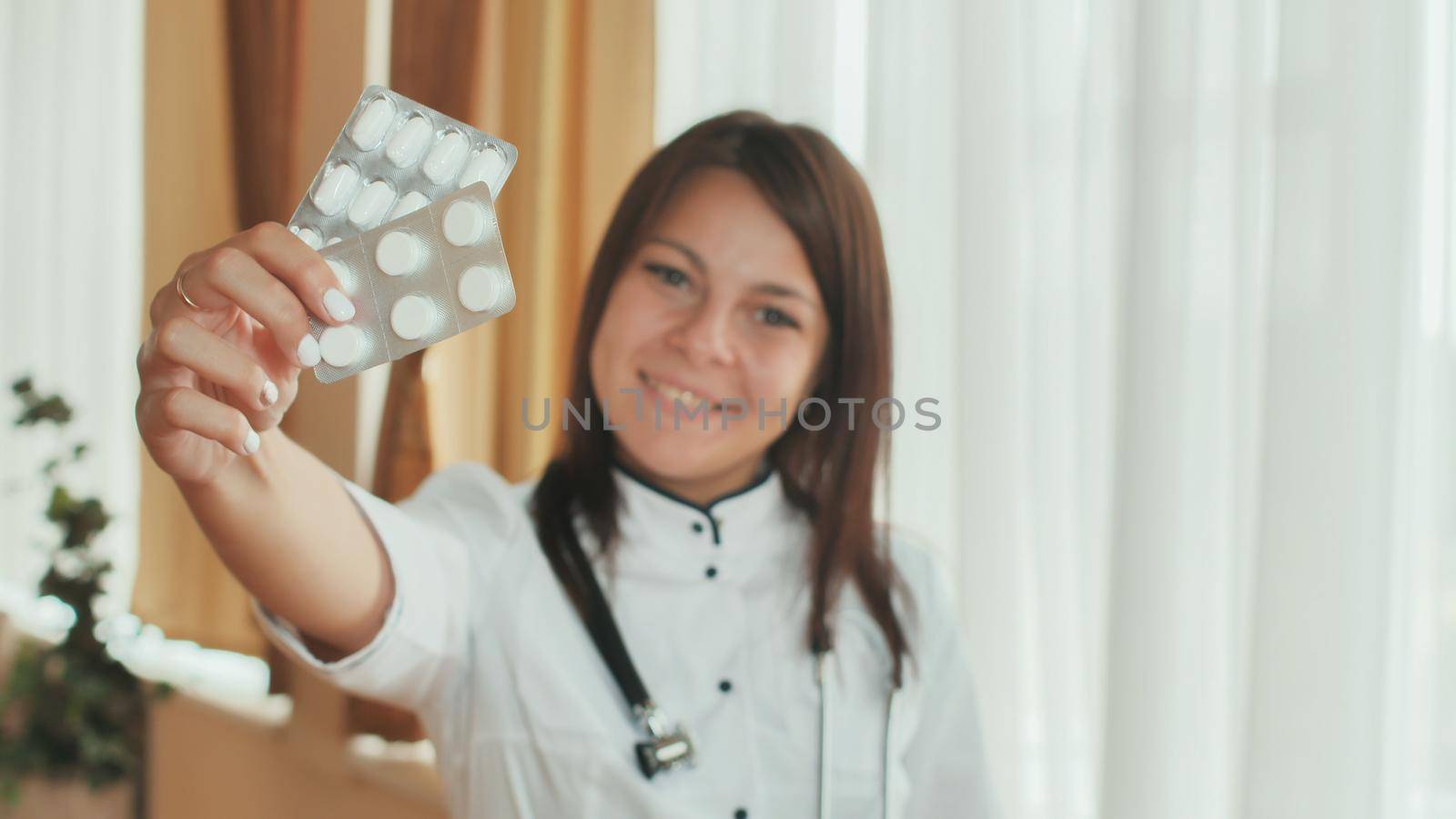 A young girl doctor demonstrates in the hands of a package of pills