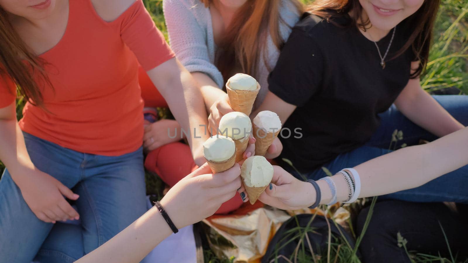 Five girls join hands clinking ice cream. Hands close-up. by DovidPro