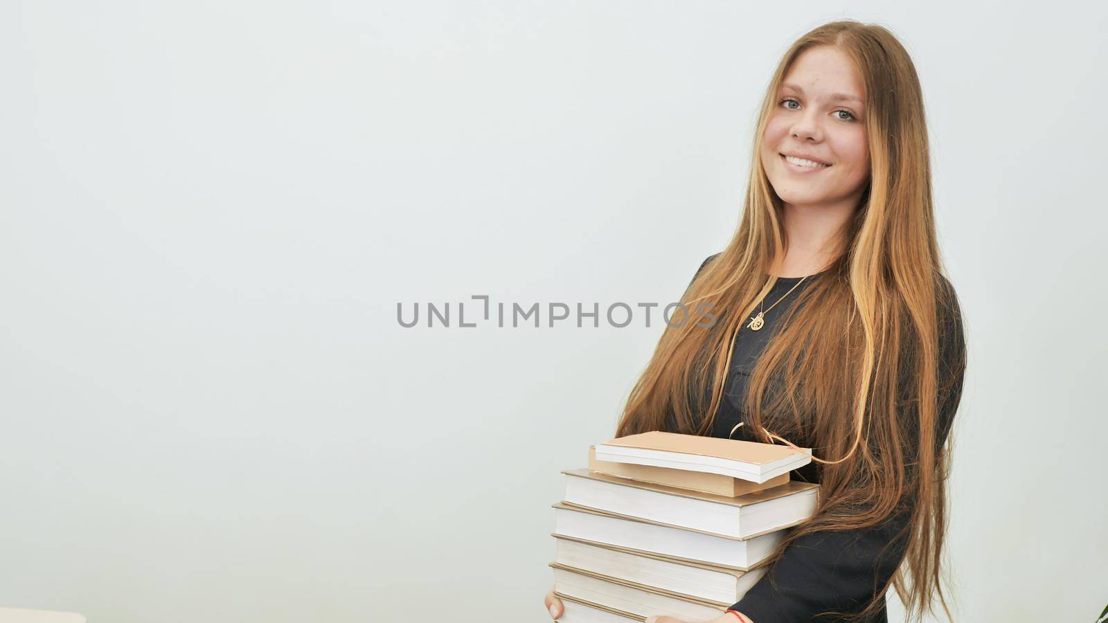 A schoolgirl in a good mood with a pile of books. by DovidPro