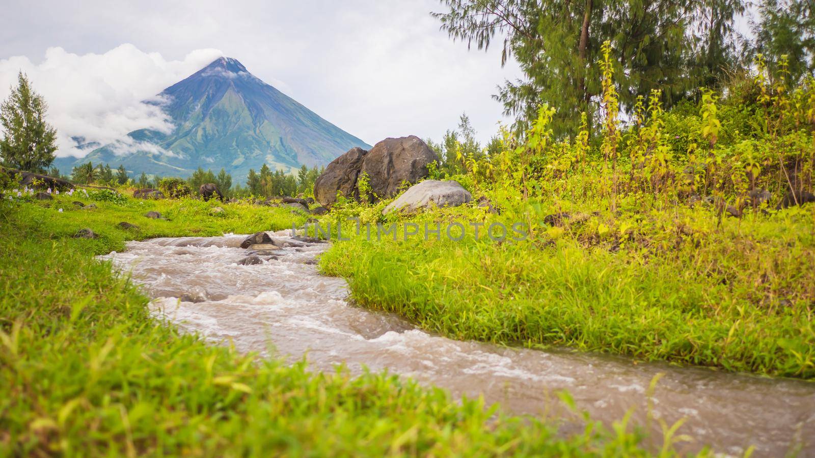 River near Mayon Volcano is an active stratovolcano in the province of Albay in Bicol Region, on the island of Luzon in the Philippines. Renowned as the perfect cone because of its symmetric conical shape. by DovidPro