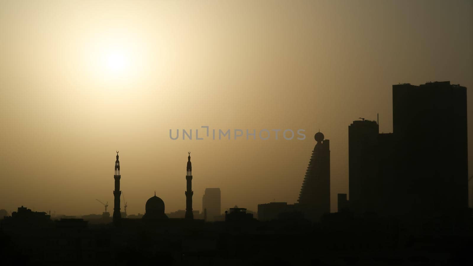 Sunrise in the morning in Dubai. Silhouettes of buildings and Moslem mosque. by DovidPro